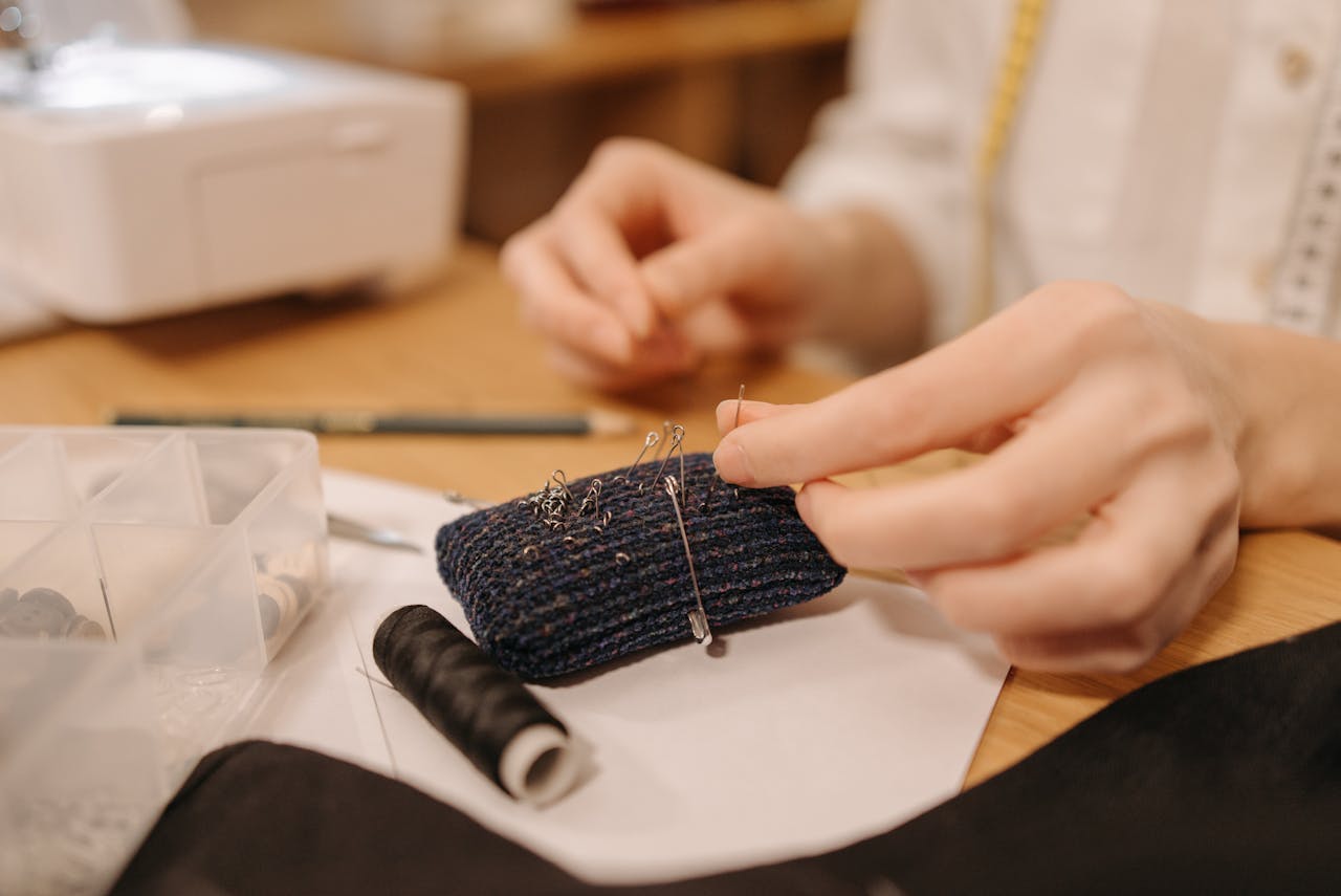brand-02 Hands working on sewing fabric with pins and needles, close-up view.